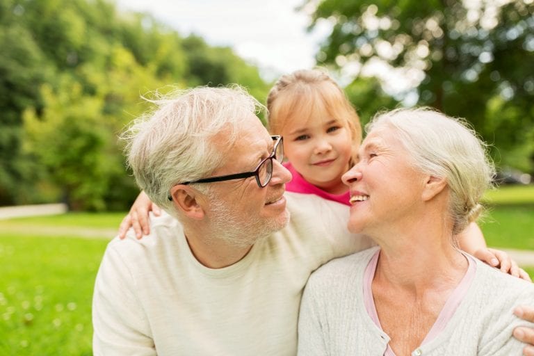 senior grandparents and granddaughter at park